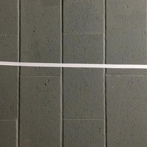 A white line taped on a grey brick wall
